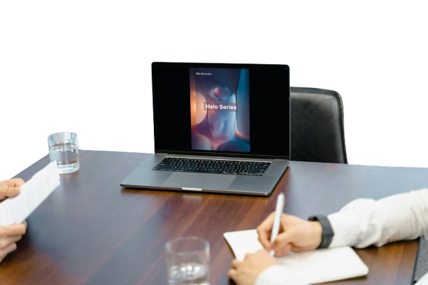 Two people at a conference table with a laptop displaying 'Hero Serum' on the screen.